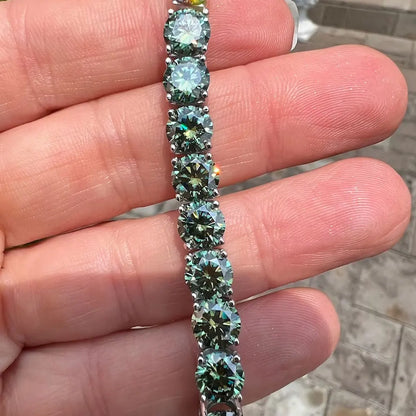 Close-up of a hand holding a bracelet with green gemstones.