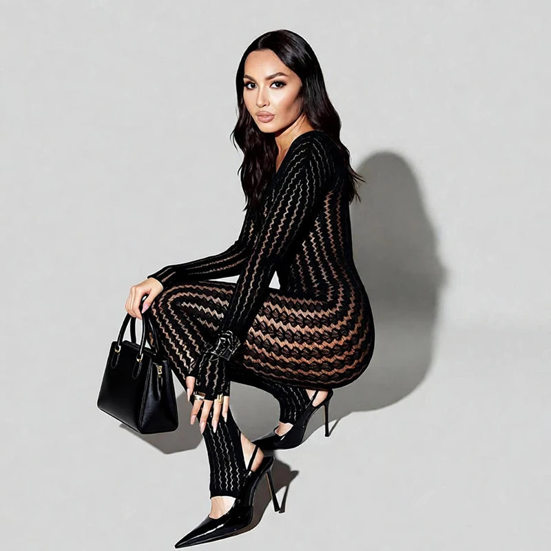 Woman wearing a black patterned dress sitting on a light gray background