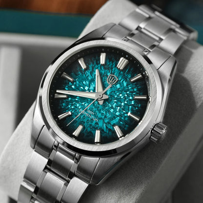 A close-up of a stainless steel wristwatch with a textured teal and turquoise sunburst dial, displayed on a gray cushion.