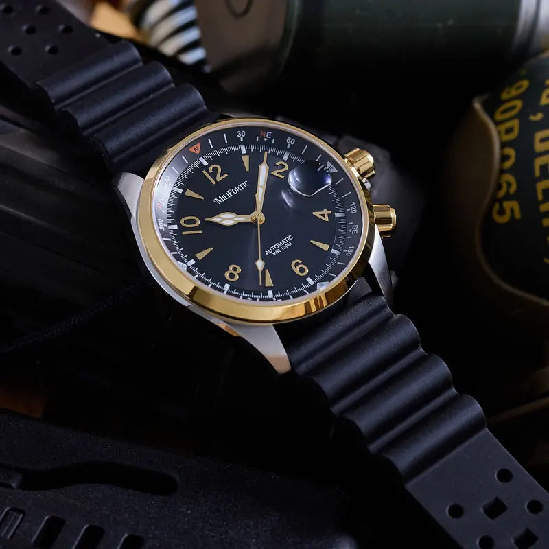 A close-up of an Altimete automatic watch with a black dial, gold-tone case, and black rubber strap, resting on a dark textured surface.