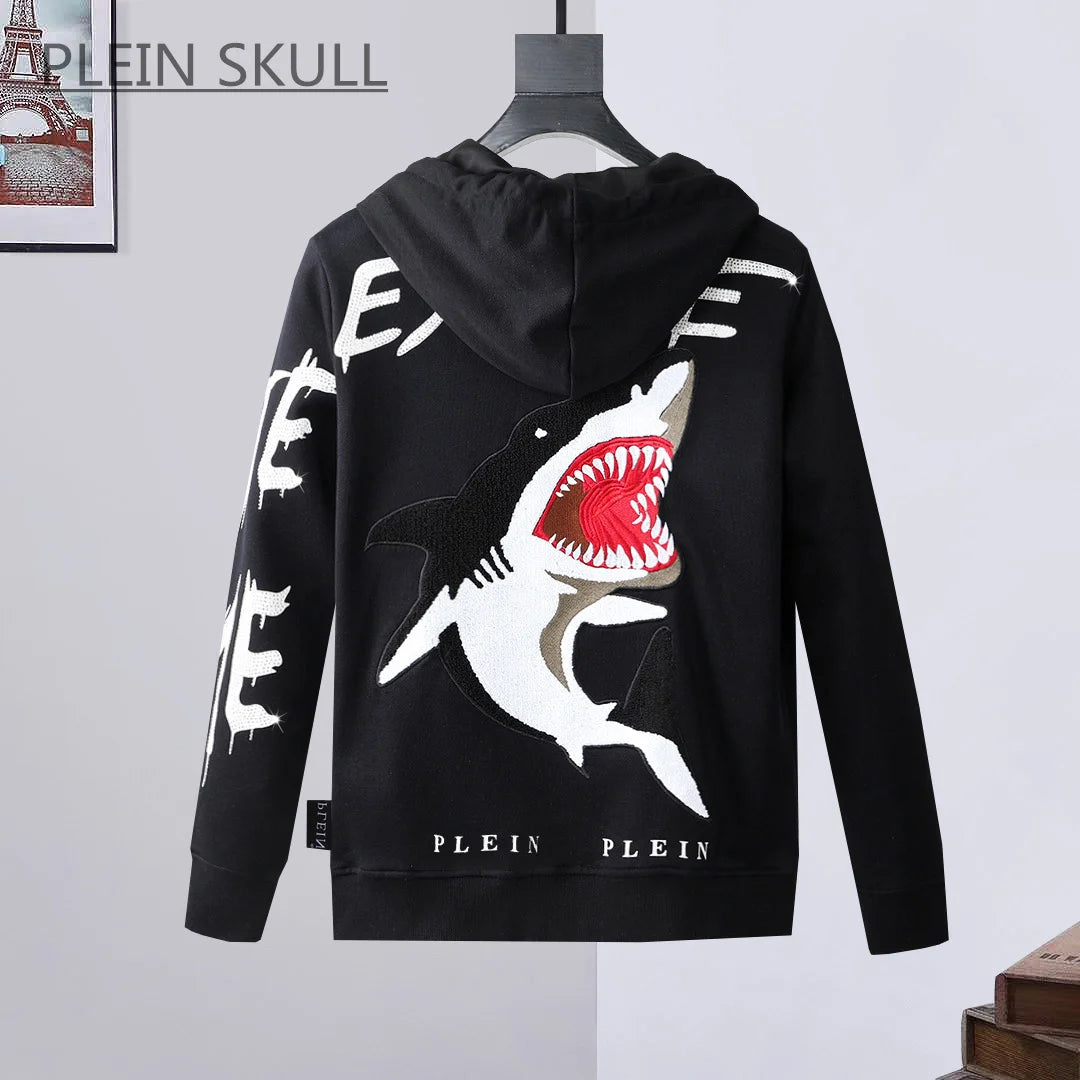 A black long-sleeve hoodie with a large shark graphic on the back, hanging on a black hanger against a light gray wall. The hoodie features white distressed text on the sleeves and 'PLEIN PLEIN' printed near the hem.