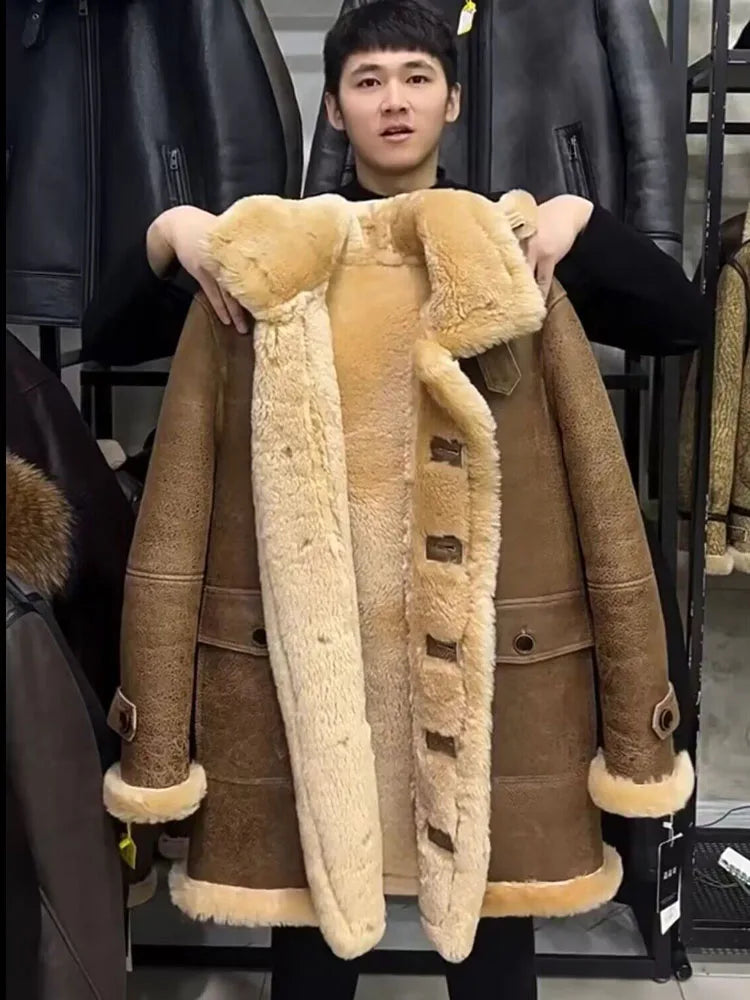 A man in a black shirt holds up a brown shearling coat with a thick cream-colored fur lining and trim. The coat features large button closures down the front and a plush collar.