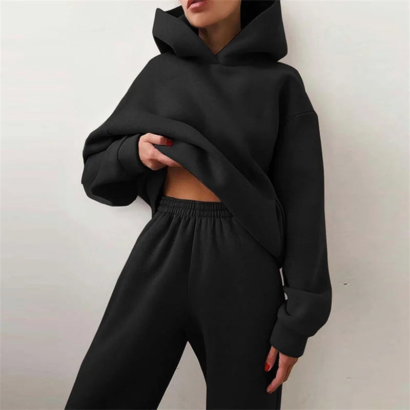 Person wearing a black hoodie and black pants against a white background