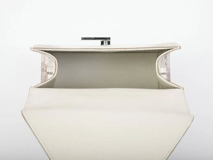 An open cream-colored leather clutch bag with a structured geometric shape, featuring a light beige interior lining and a silver-tone metal clasp at the top, set against a plain white background.