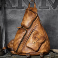 A distressed brown leather duffel-style backpack with multiple zippered compartments and a front pocket, displayed on a rustic wooden surface against a dark textured wall.