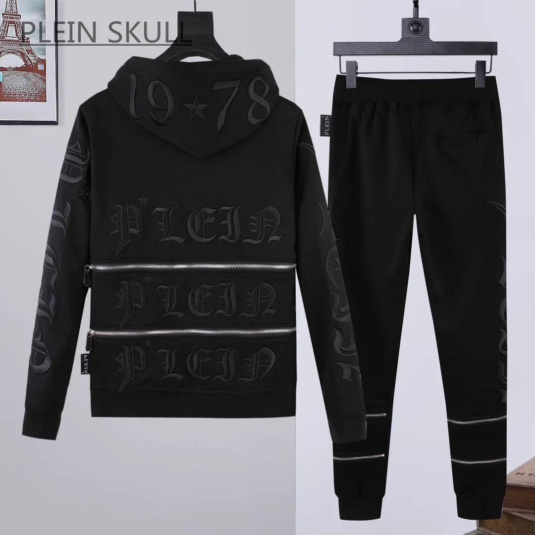 A black two-piece tracksuit set featuring a hooded sweatshirt and matching jogger pants, both decorated with dark gray Gothic lettering and horizontal metallic-looking stripe details. The hoodie is shown from the back, and the pants are shown from the side.