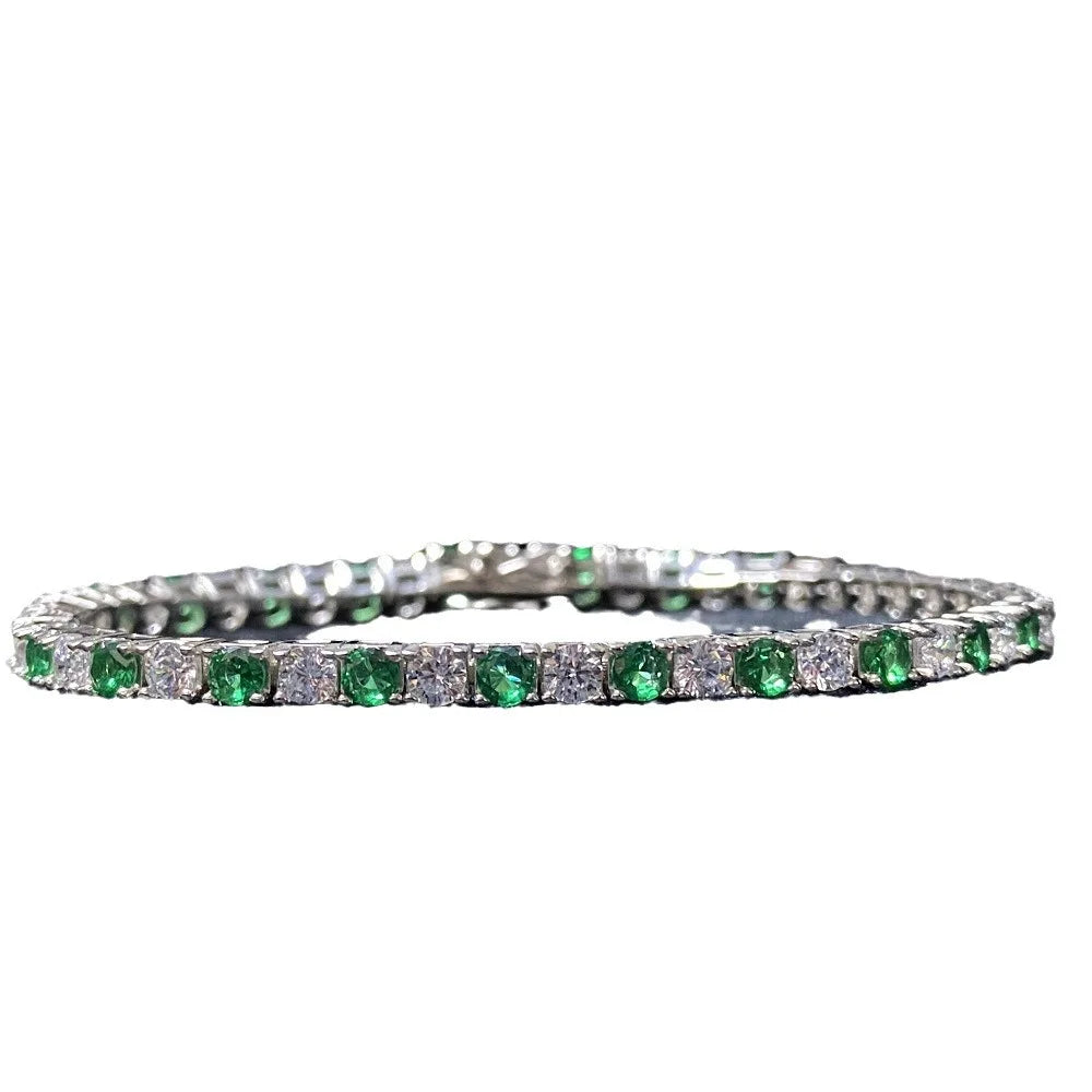 A tennis bracelet featuring round-cut green emeralds and clear stones in a silver-colored setting, shown against a plain white background.