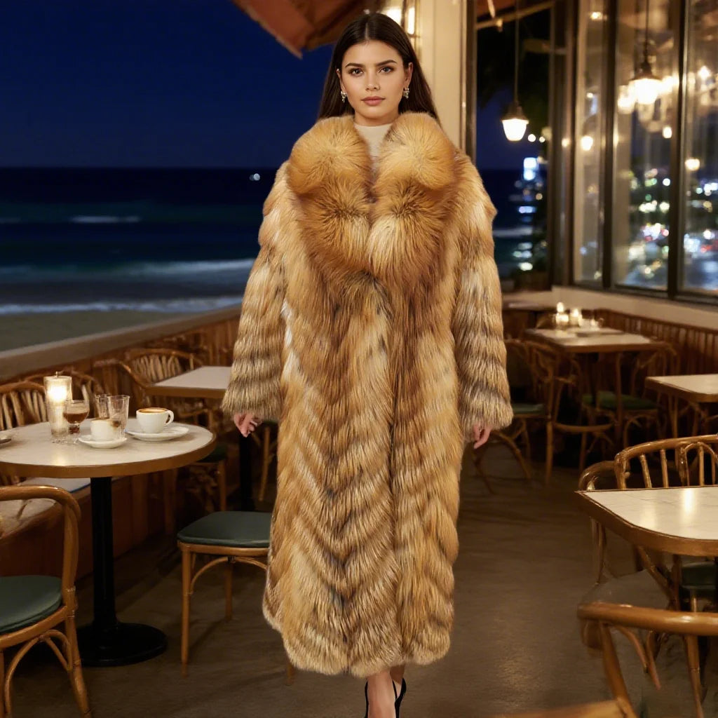 A woman models a long, luxurious fur coat with a large shawl collar in a restaurant setting with a night ocean view in the background.