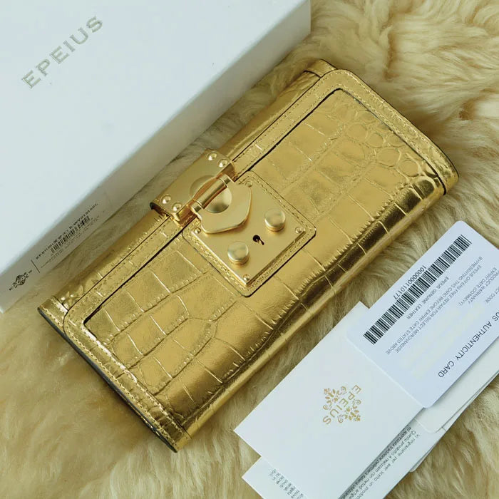 A gold faux-crocodile leather wallet with a padlock clasp, shown next to its white EPEIUS box and authenticity card on a beige faux fur background.