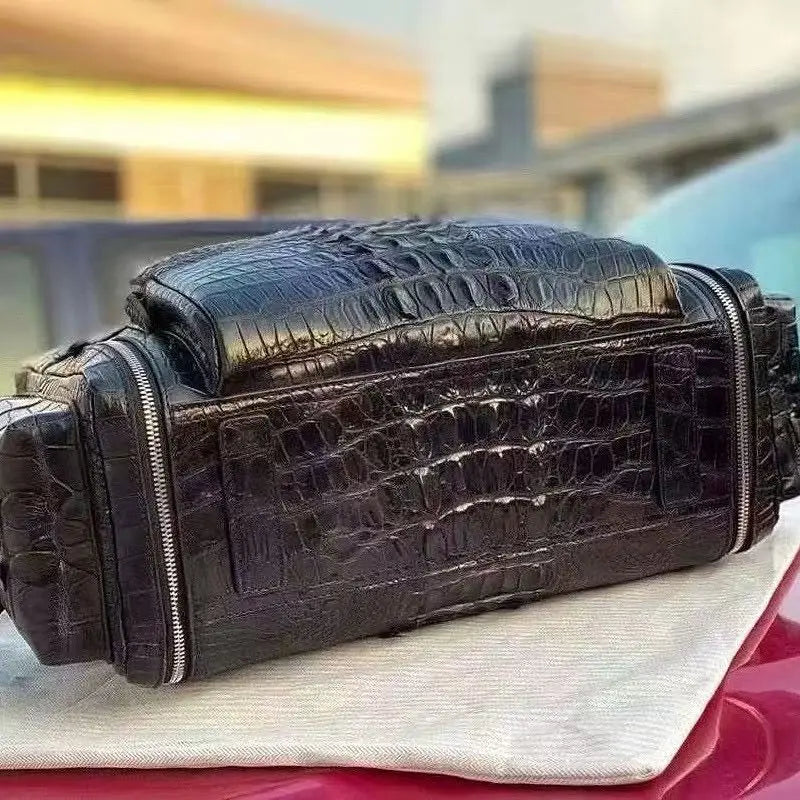 A dark brown alligator leather shoulder bag resting on a white cloth on top of a red car, with a blurred outdoor background.