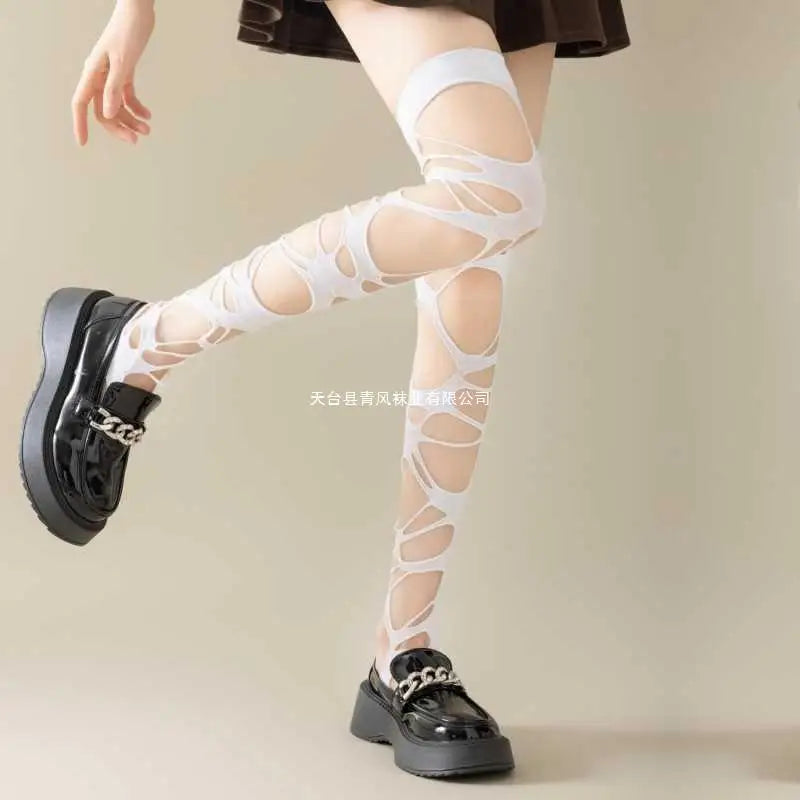 White sheer cutout thigh-high socks worn with black platform loafers, shown on a model's legs against a plain beige studio background.