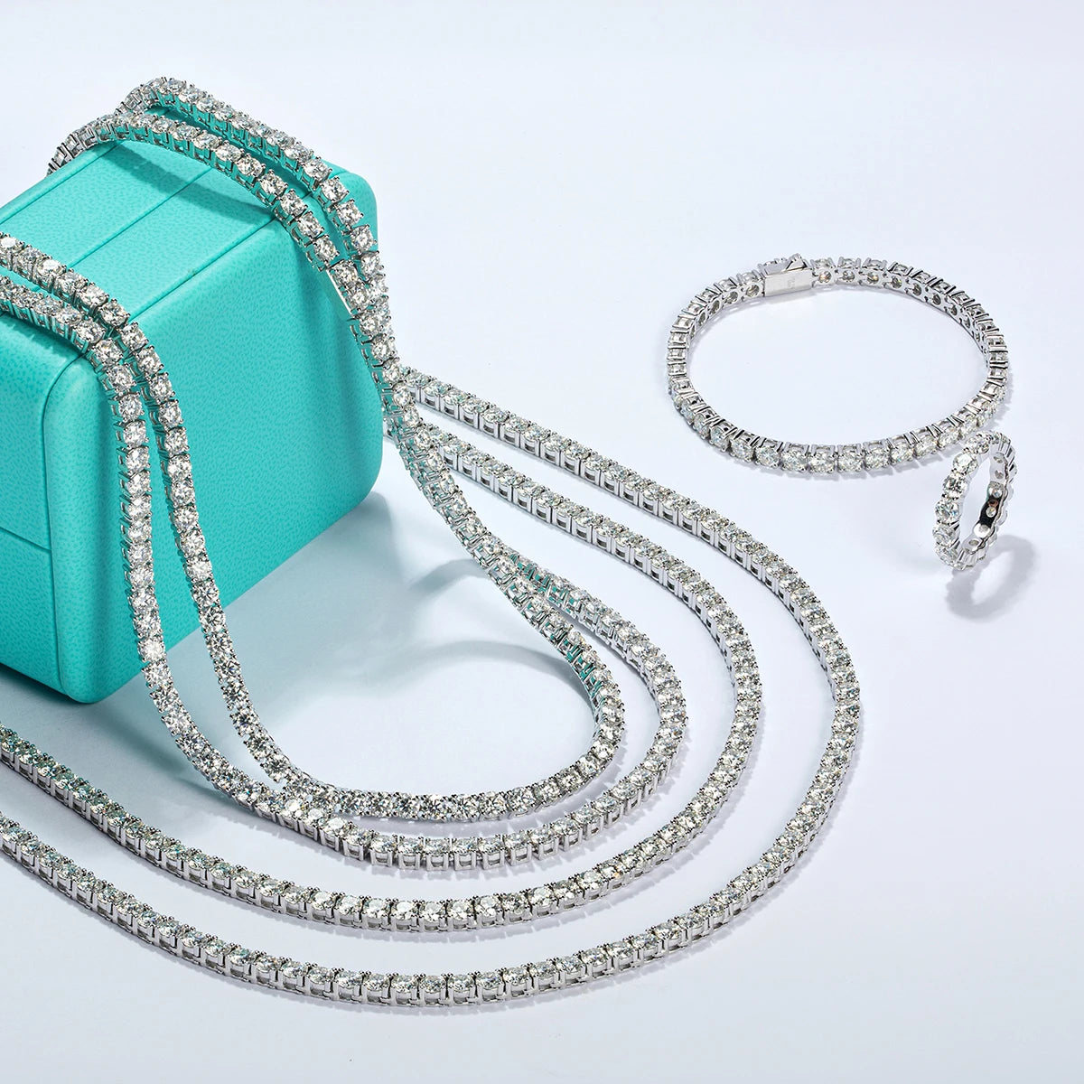 Diamond necklace and bracelet set with a turquoise box on a light gray background
