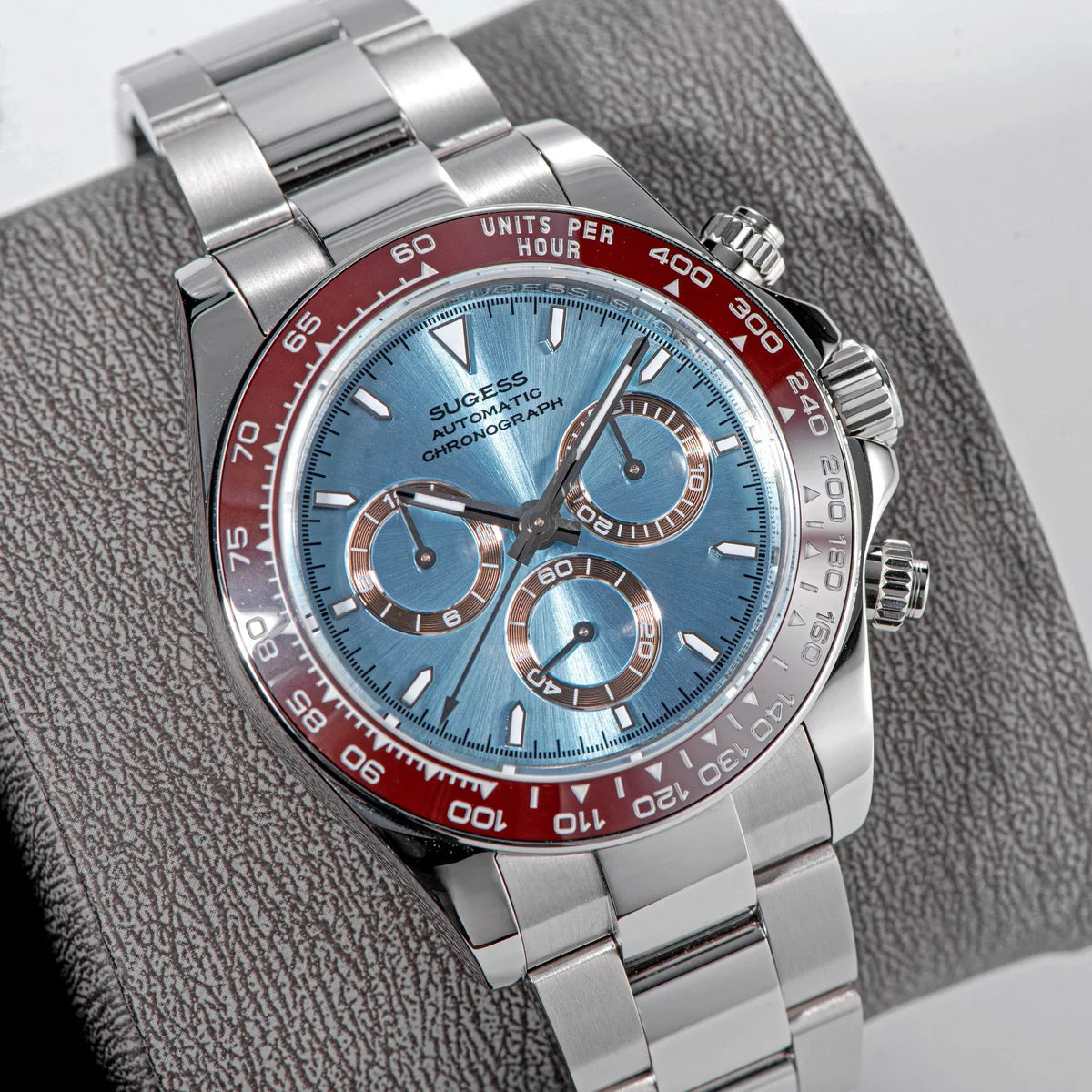 Silver and red watch with blue face on a textured surface