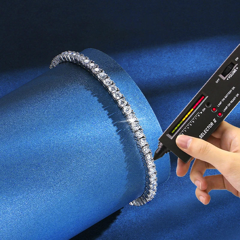 Hand holding a diamond detector over a diamond-studded ring on a blue fabric background