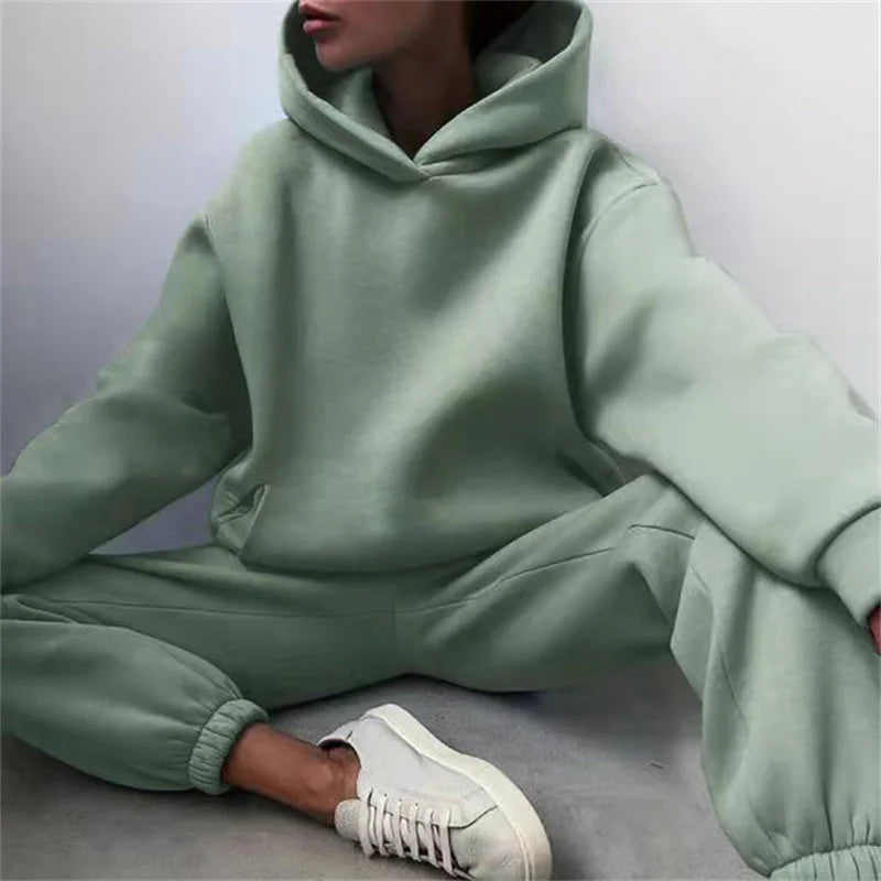 Person wearing a light green hoodie and pants sitting on a gray surface.
