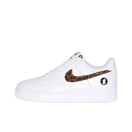 A white Nike Air Force 1 sneaker featuring a brown and black leopard print Swoosh on the side and a black circular logo patch on the heel.