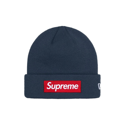 A navy blue ribbed knit beanie hat featuring a red rectangular Supreme box logo patch on the front cuff and a small white New Era flag logo on the side, set against a plain white background.