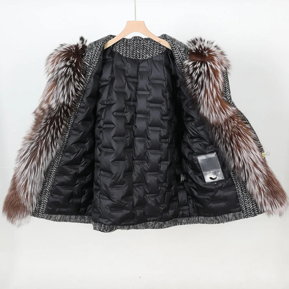 A black quilted puffer jacket with a large brown and white faux-fur collar, hanging on a wooden hanger against a plain white background.