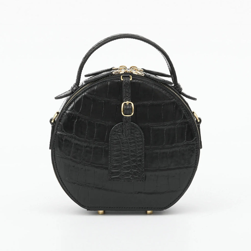 A black crocodile-embossed leather handbag with a top handle, gold-tone hardware, and a front hanging tag, photographed on a clean white background.