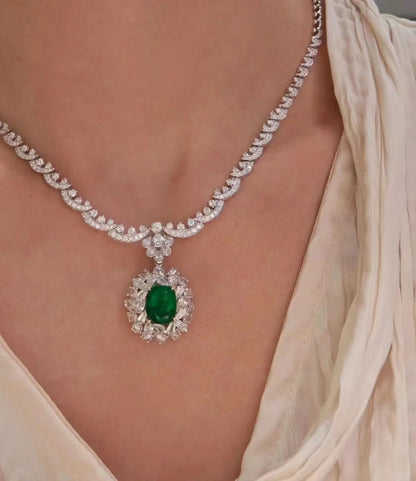 Delicate necklace with a green gemstone pendant on a person wearing a light-colored top.
