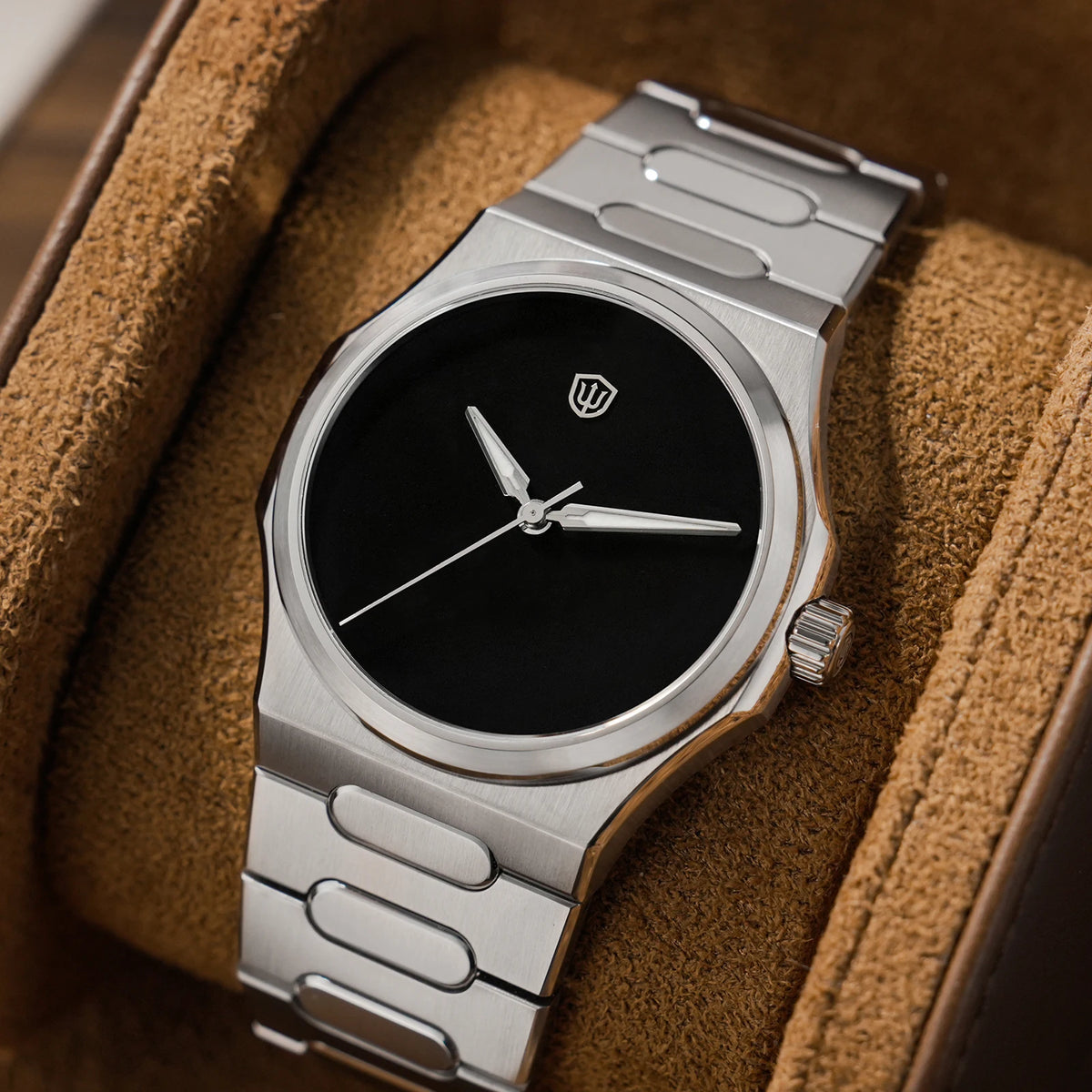 Silver watch with black face on a brown textured surface