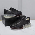 Black textured sneakers on a white surface with a gray background