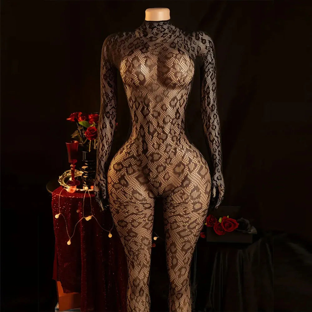 A long-sleeve, high-neck snakeskin-patterned bodysuit displayed on a mannequin against a dark studio background, with decorative red roses and a draped table to the side.
