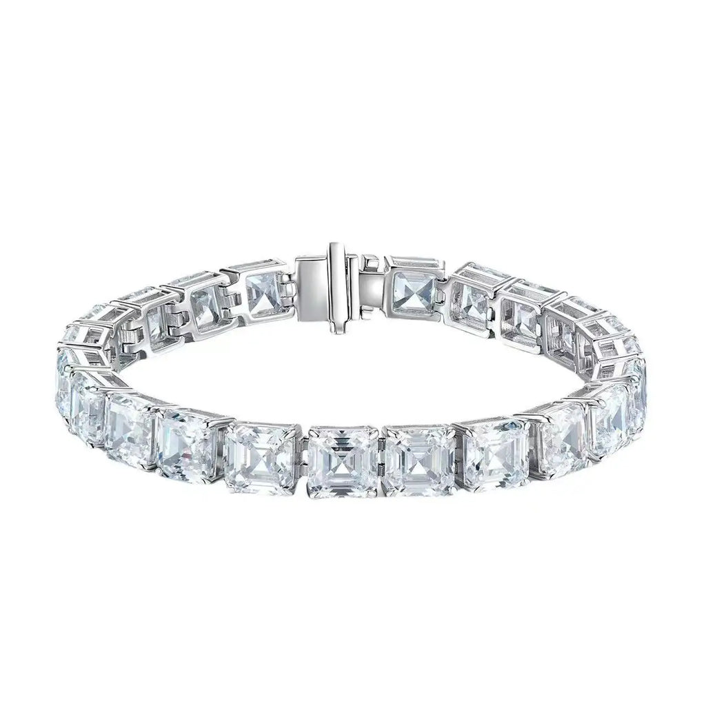 A silver tennis bracelet featuring a row of square-cut clear gemstones in a bezel setting, with a polished clasp closure, shown against a plain white background.
