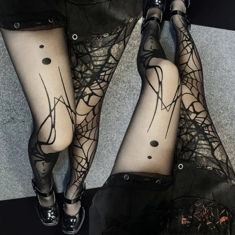 Two pairs of legs wearing black lace tights with spider web patterns on a gray floor.