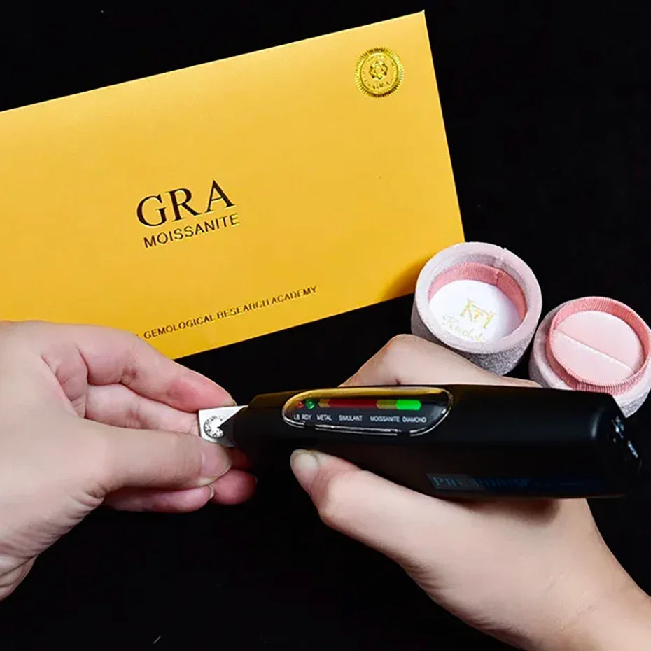 Person using a gemstone analyzer with two pink gemstones and a yellow GRA box in the background.