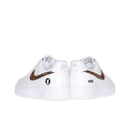 A pair of white Nike Air Force 1 Low sneakers featuring a brown and black leopard print Swoosh and a black circular 8-balls logo on the side, with a small black Supreme box logo on the heel.