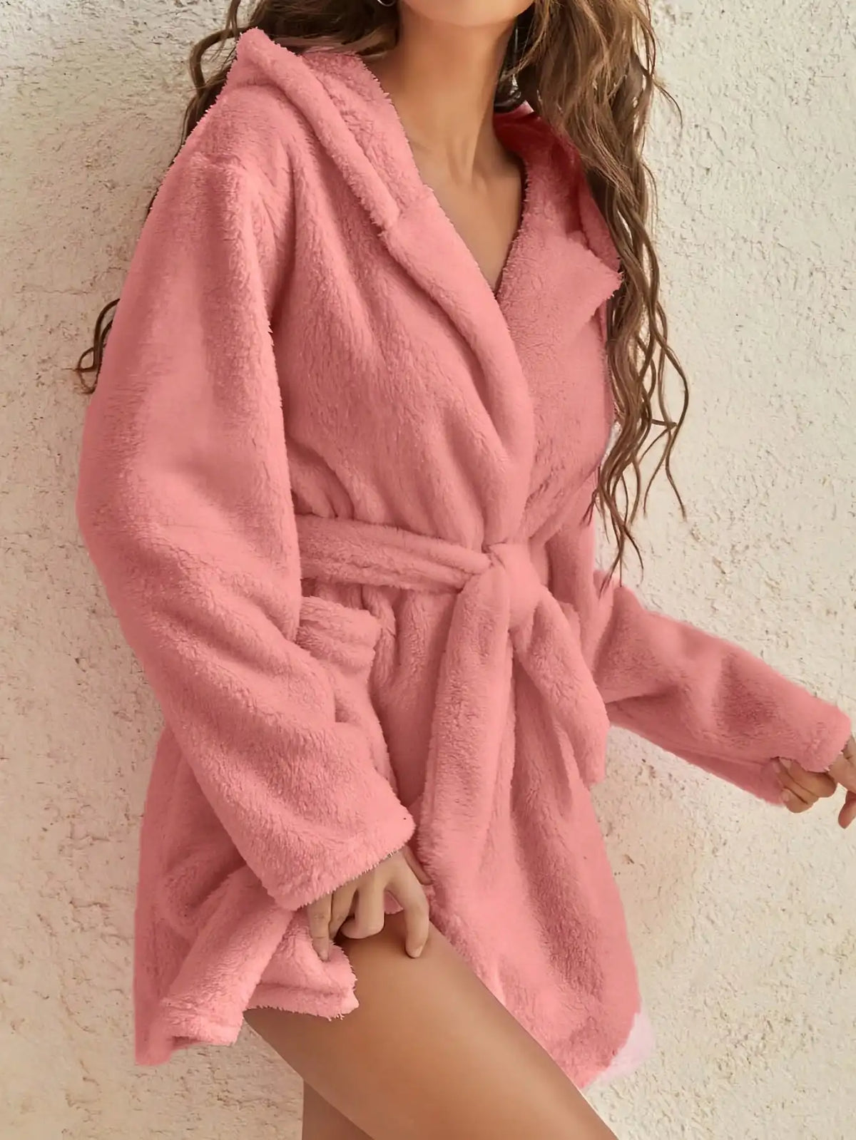 Person wearing a pink robe against a neutral background