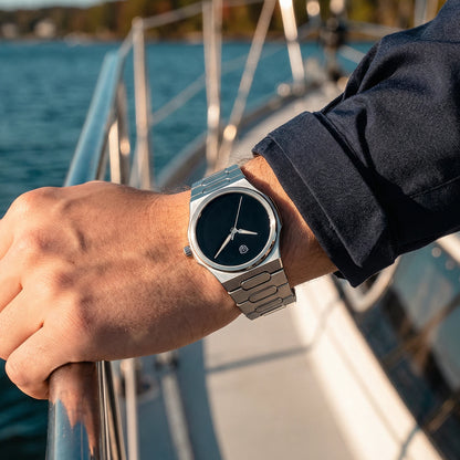 Person wearing a silver watch on a boat with water in the background