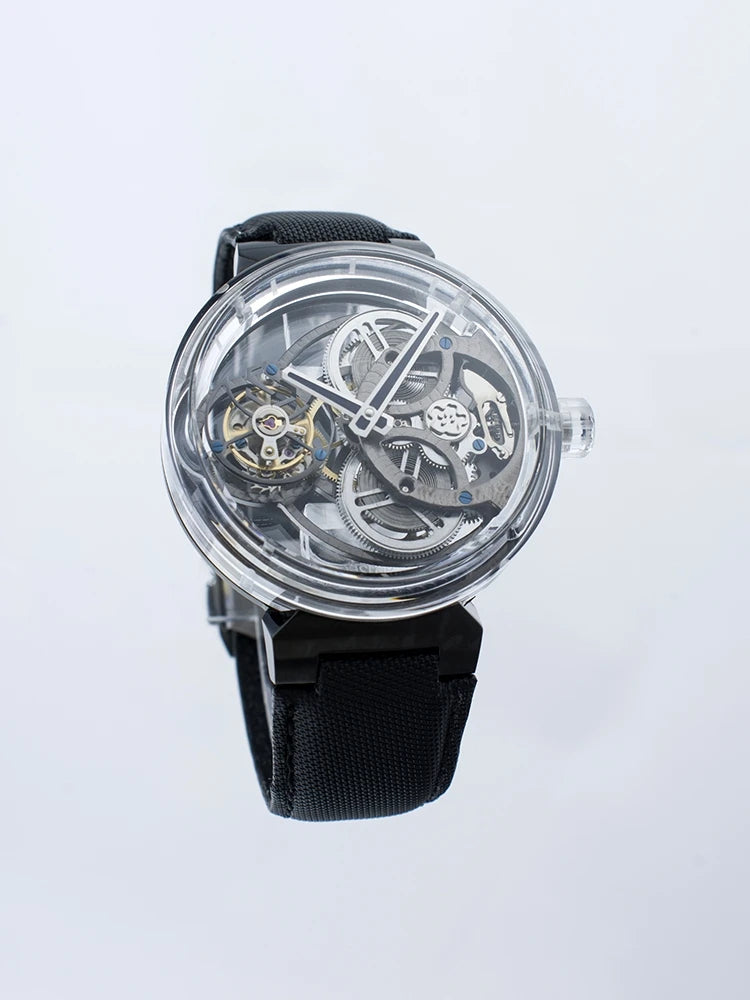 A skeleton watch with a black strap, clear case, and visible mechanical gears and movement inside, shown against a light gray background.