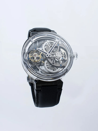 A skeleton watch with a black strap, clear case, and visible mechanical gears and movement inside, shown against a light gray background.