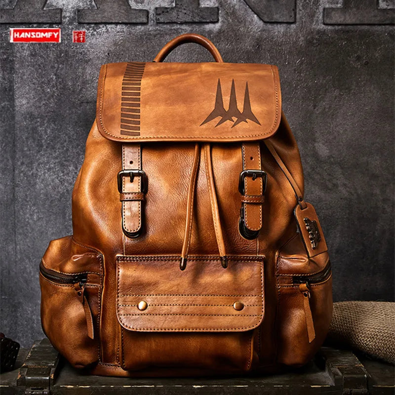 A brown leather backpack with multiple front pockets, buckle details, and an embossed bat logo on the flap, displayed against a dark textured wall.