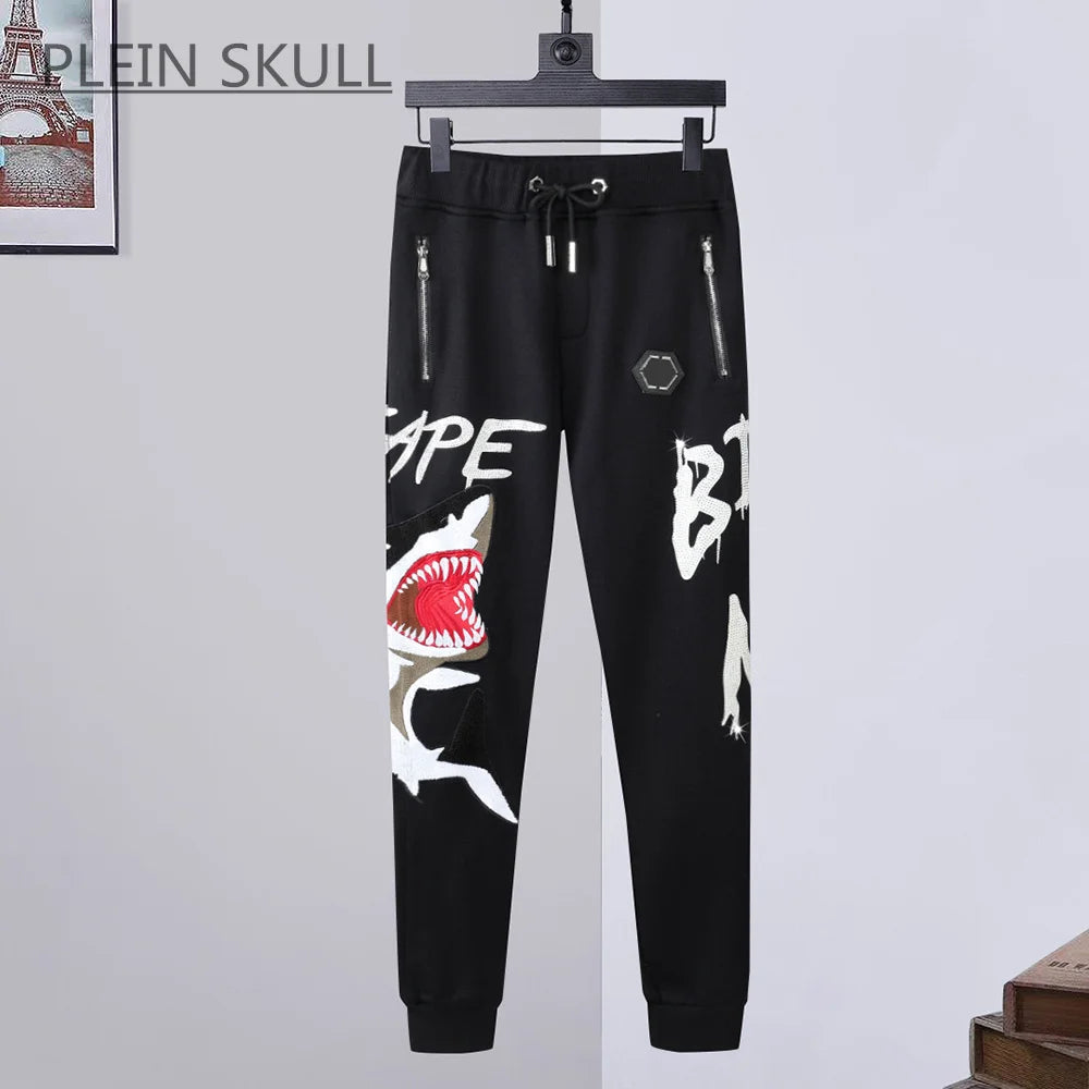 Black pants with graphic designs on a hanger against a light gray background