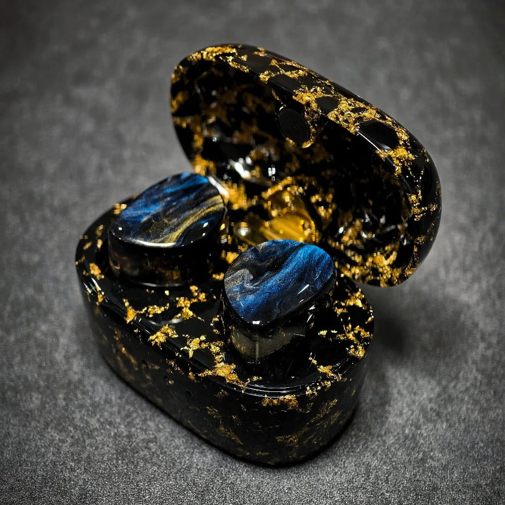 Black and gold wireless earbuds in a matching case on a gray background
