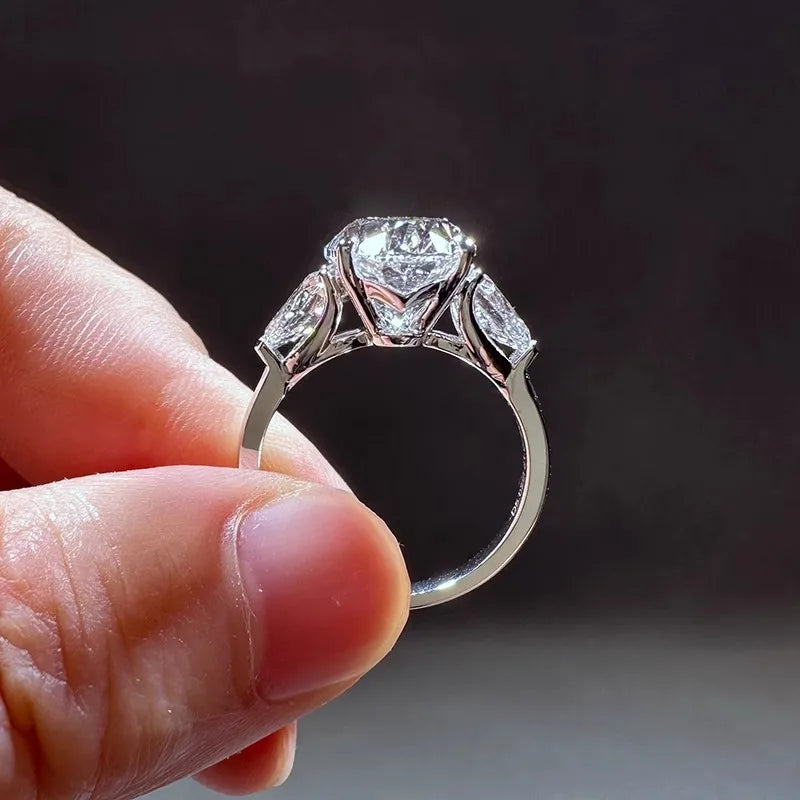 Diamond ring held between fingers against a dark background