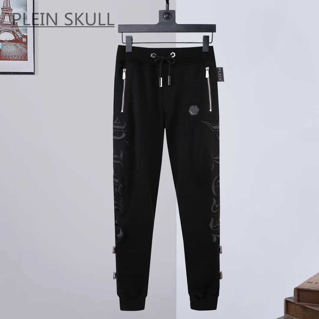 Black jogger pants with embroidery on a hanger against a light gray background