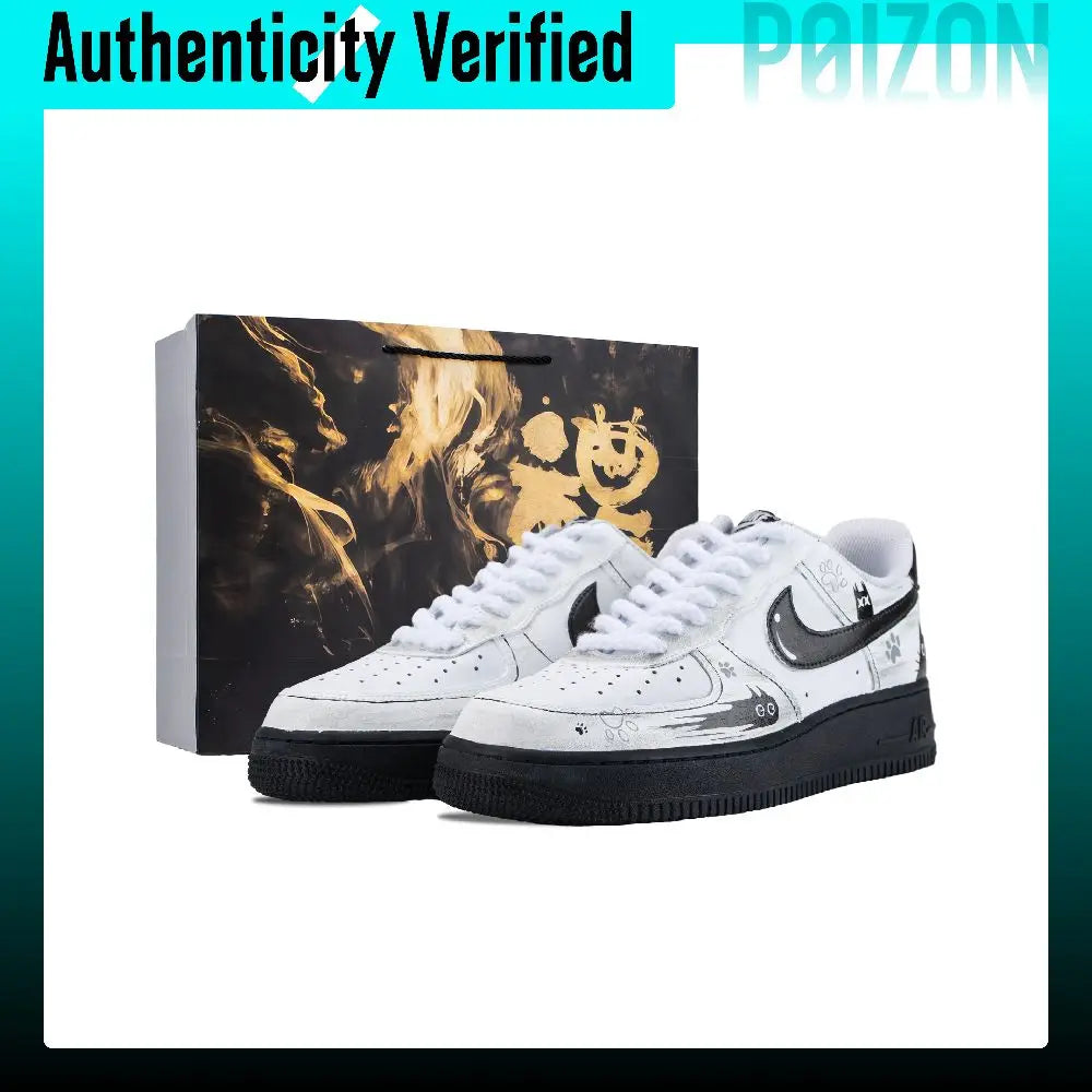 A pair of white Nike Air Force 1 Low sneakers with black and gold Halloween-themed graphics, displayed next to their black and gold gift box on a white background with a teal border.