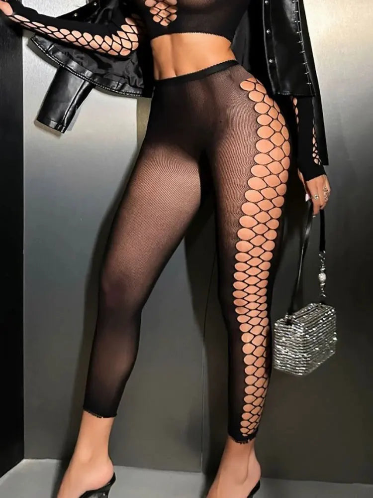Person wearing black fishnet stockings with a patterned design, standing against a neutral background.