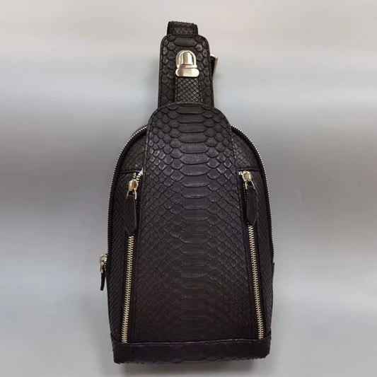 Black textured sling bag with gold zippers on a light gray background
