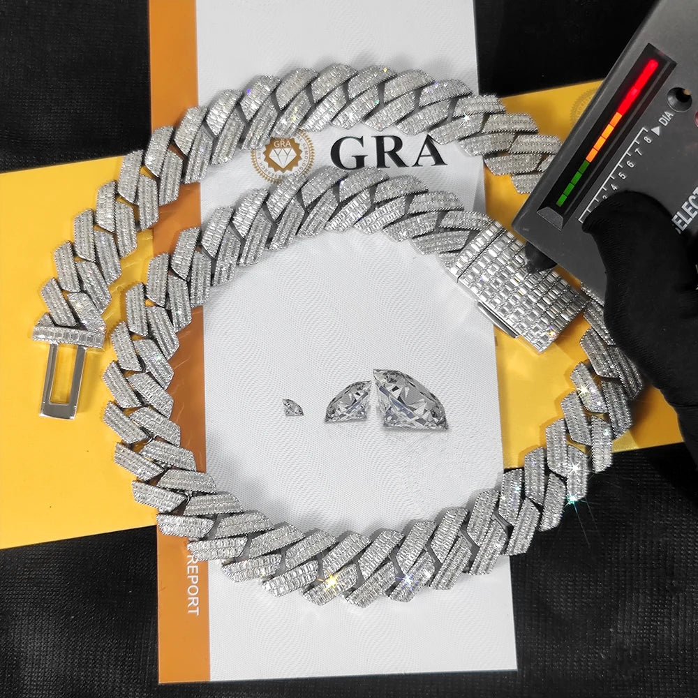 A chunky silver-toned Cuban link chain bracelet covered in clear stones, arranged on top of a white and yellow report card. A black gloved hand holds a spectrometer over the bracelet, and two loose clear stones are placed in the center.