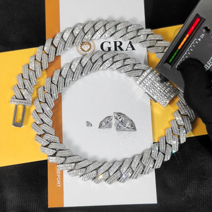A chunky silver-toned Cuban link chain bracelet covered in clear stones, arranged on top of a white and yellow report card. A black gloved hand holds a spectrometer over the bracelet, and two loose clear stones are placed in the center.