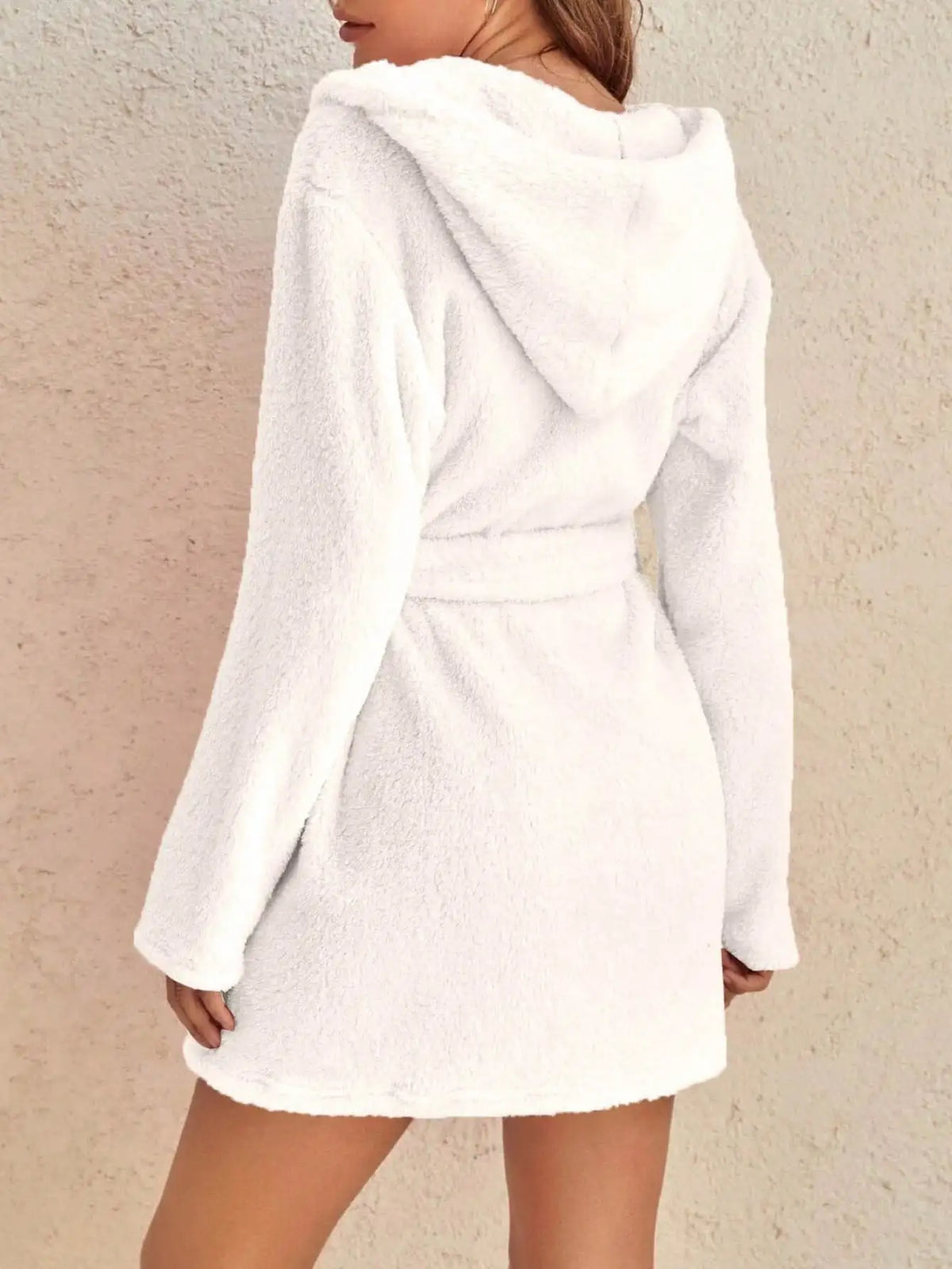 White hooded robe worn by a person on a beige background