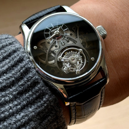 Close-up of a person wearing a black wristwatch with a visible mechanical movement.