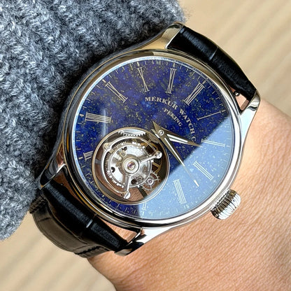 Merkur watch with blue face and black strap on wrist