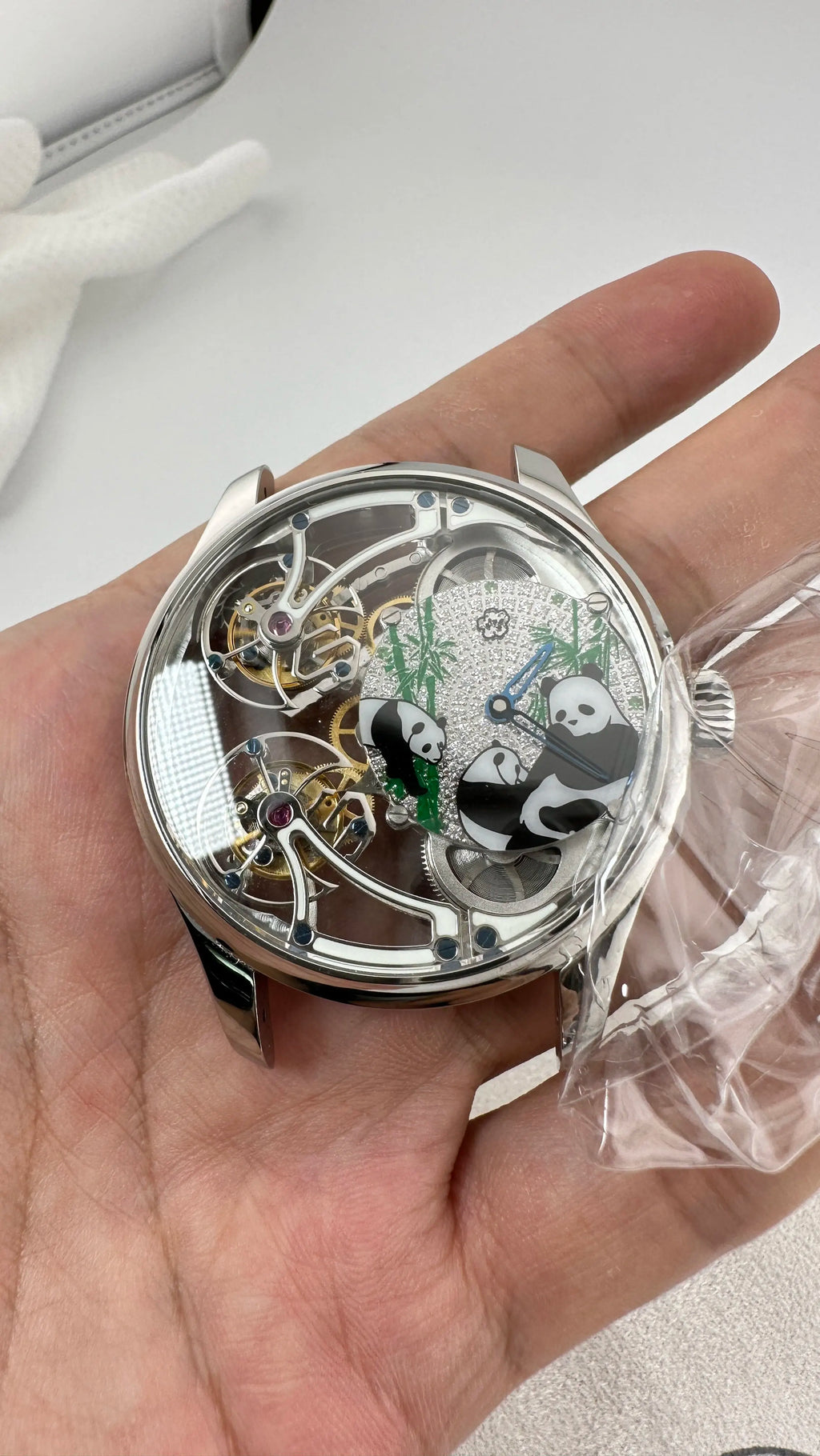 Close-up of a mechanical watch with panda design held in a hand.