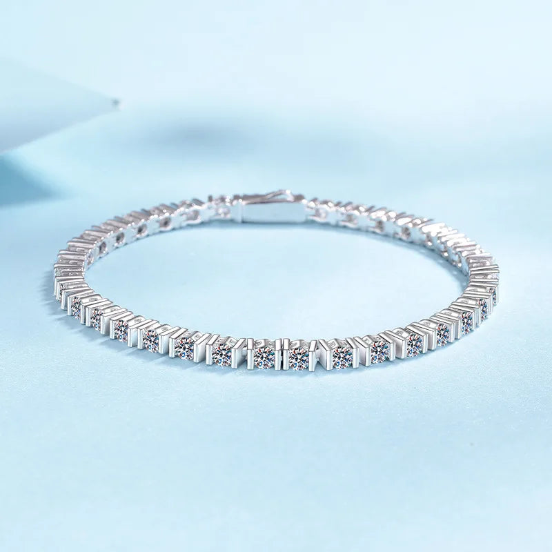 A silver tennis bracelet with rectangular baguette and round-cut stones, displayed on a light blue background.